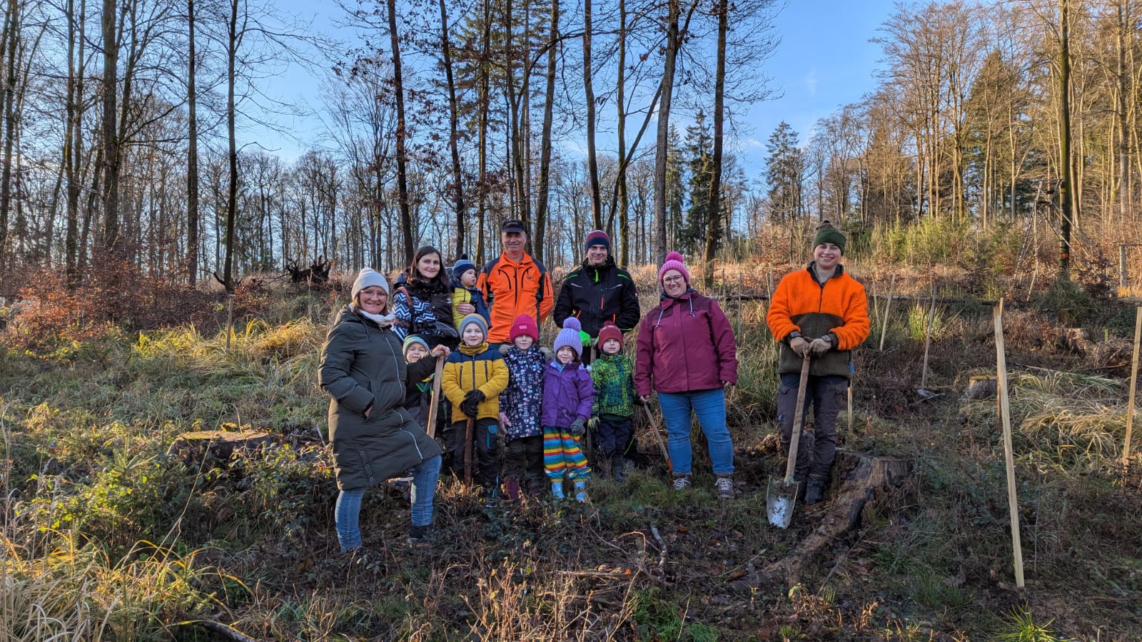 Ein Förster und Kinder einer Kindertagesstätte pflanzen zusammen Bäume.