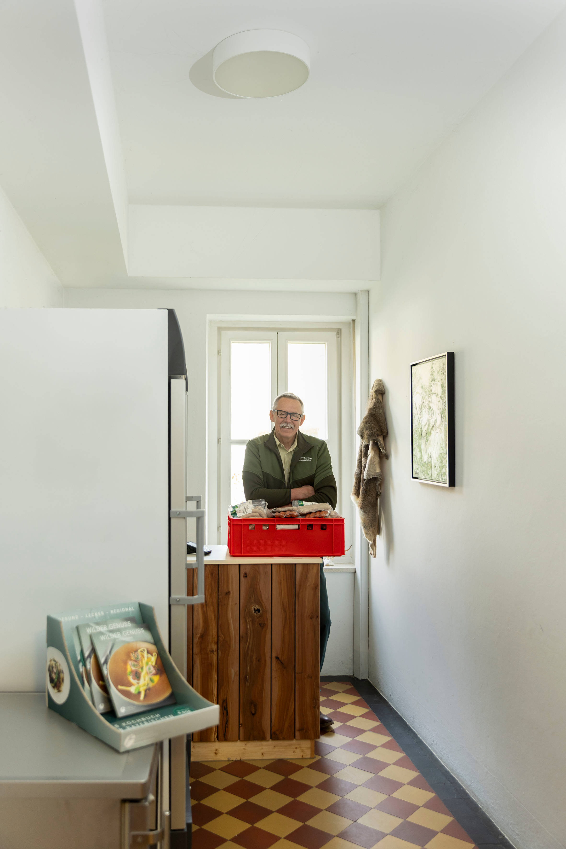 Berufsjäger steht in Wildkammer mit verpacktem Fleisch und Kühlschränken