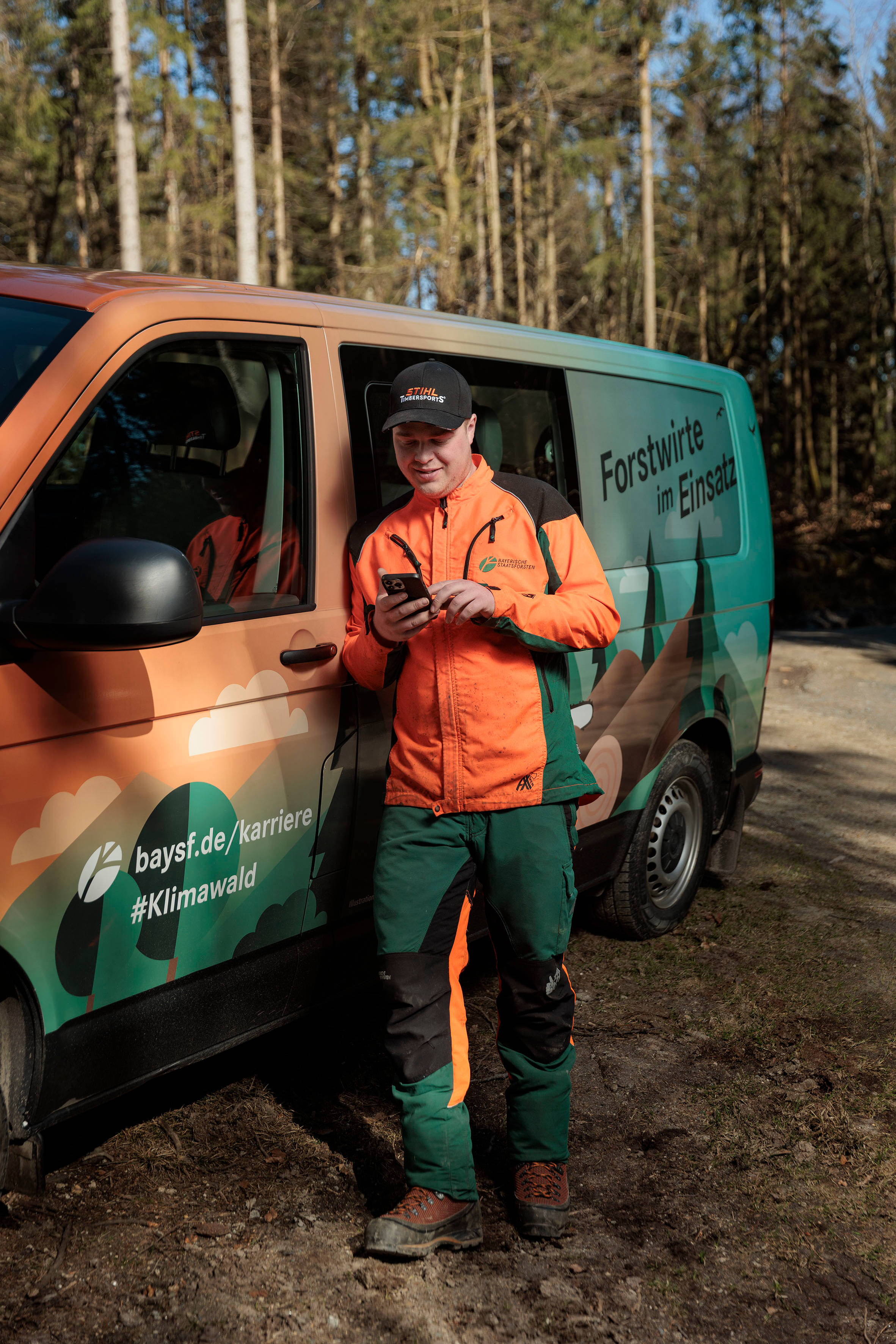 Forstwirt vor Bus mit Forstwirte im Einsatz Aufdruck