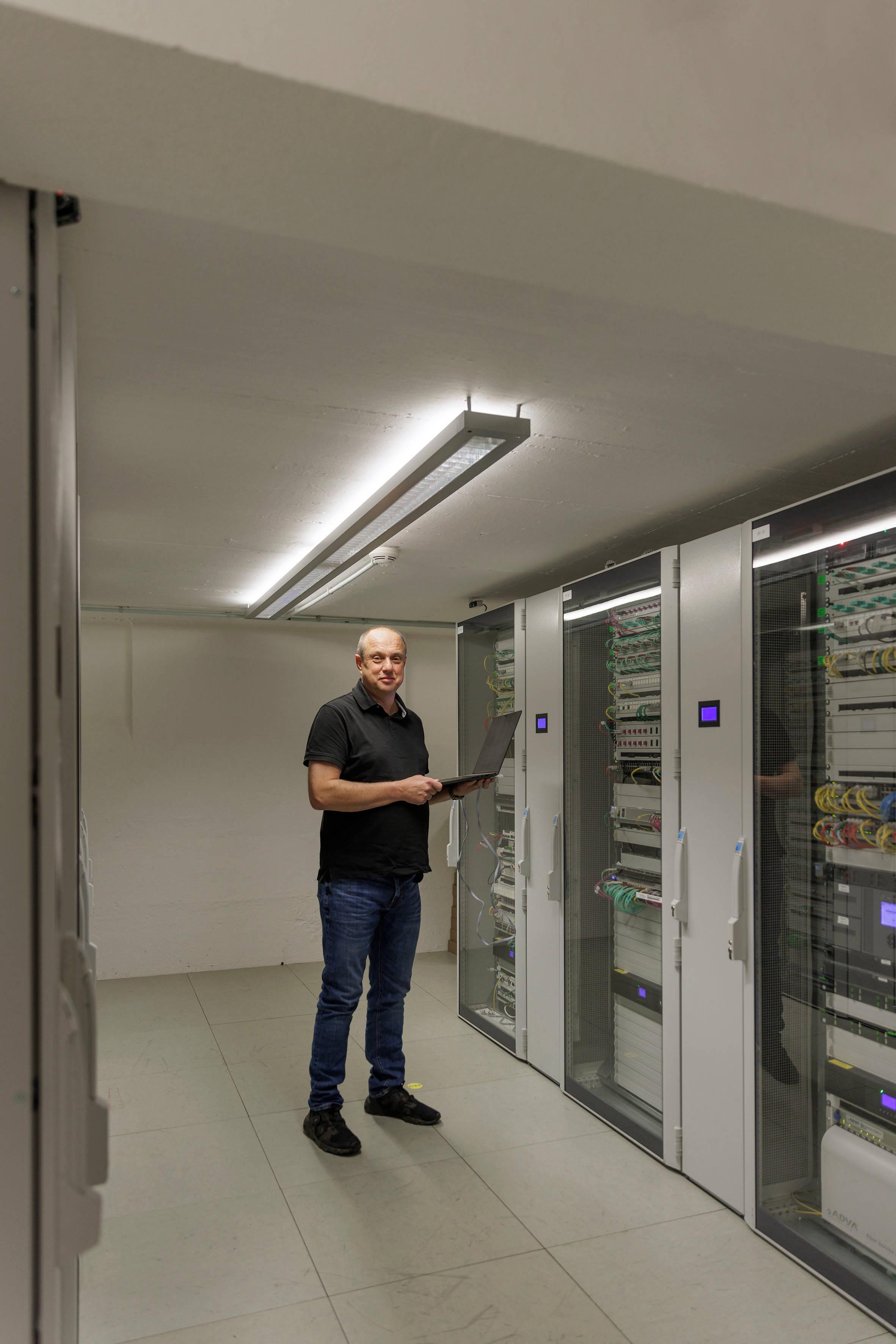 IT-Spezialist steht vor Servern in Keller