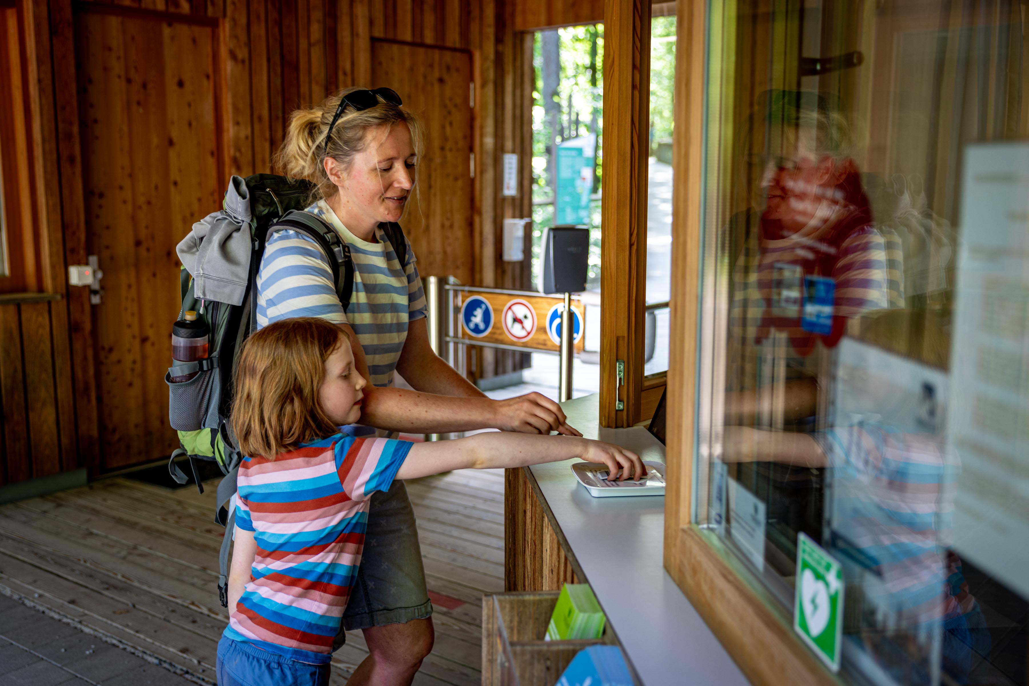Eine Frau und ein Kind kaufen Tickets für den Baumwipfelpfad Steigerwald