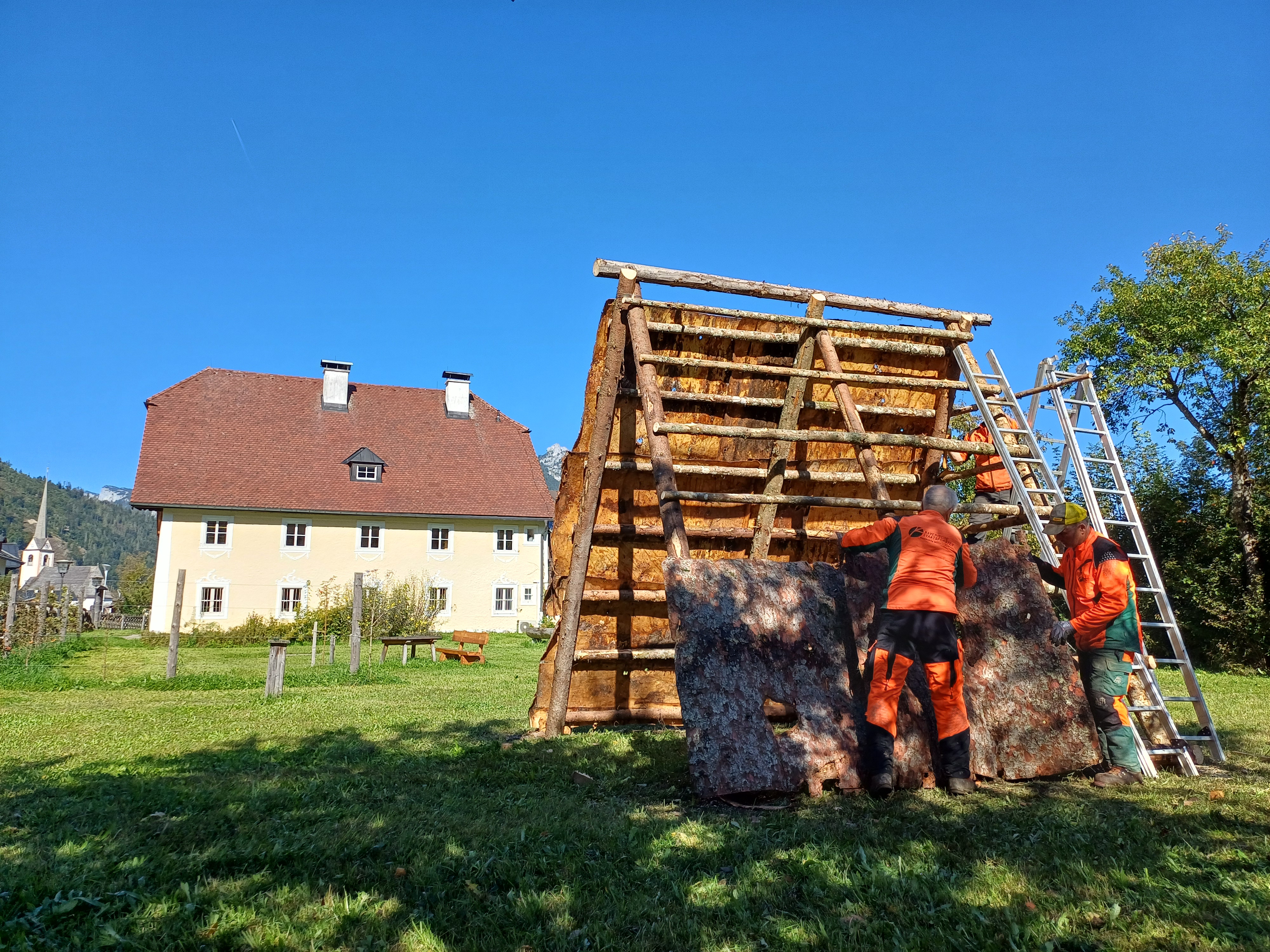 Waldarbeiter bauen im Forstbetriebsgarten einen historischen Rindenkobel nach