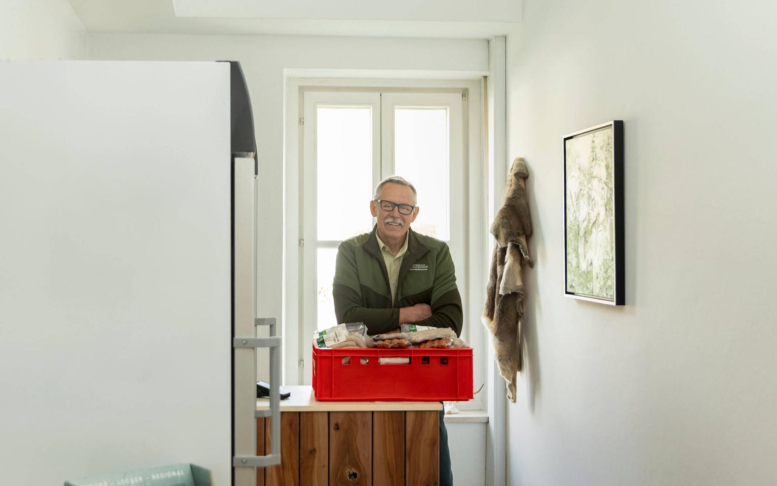 Berufsjäger steht in Wildkammer mit verpacktem Fleisch und Kühlschränken