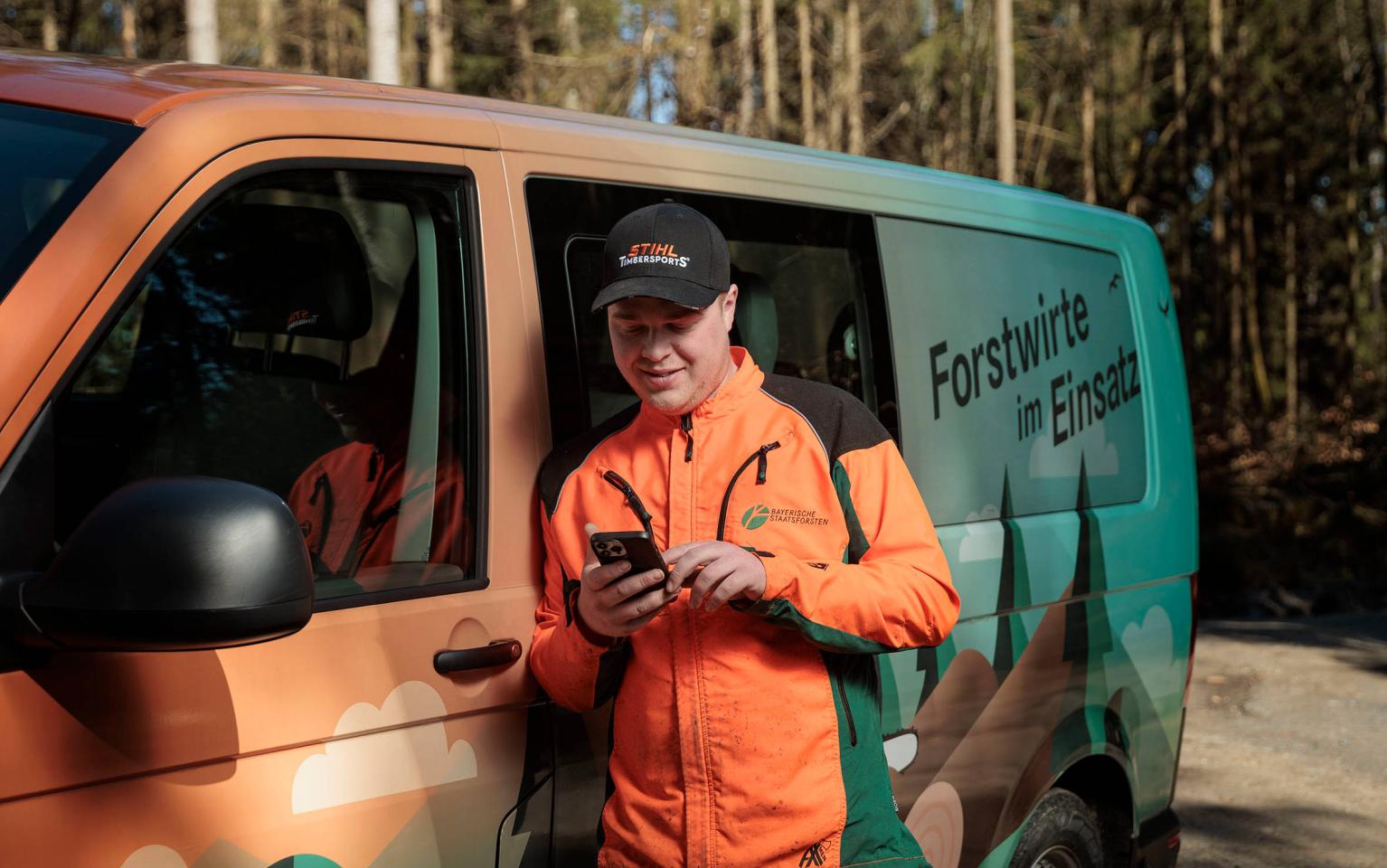 Forstwirt vor Bus mit Forstwirte im Einsatz Aufdruck