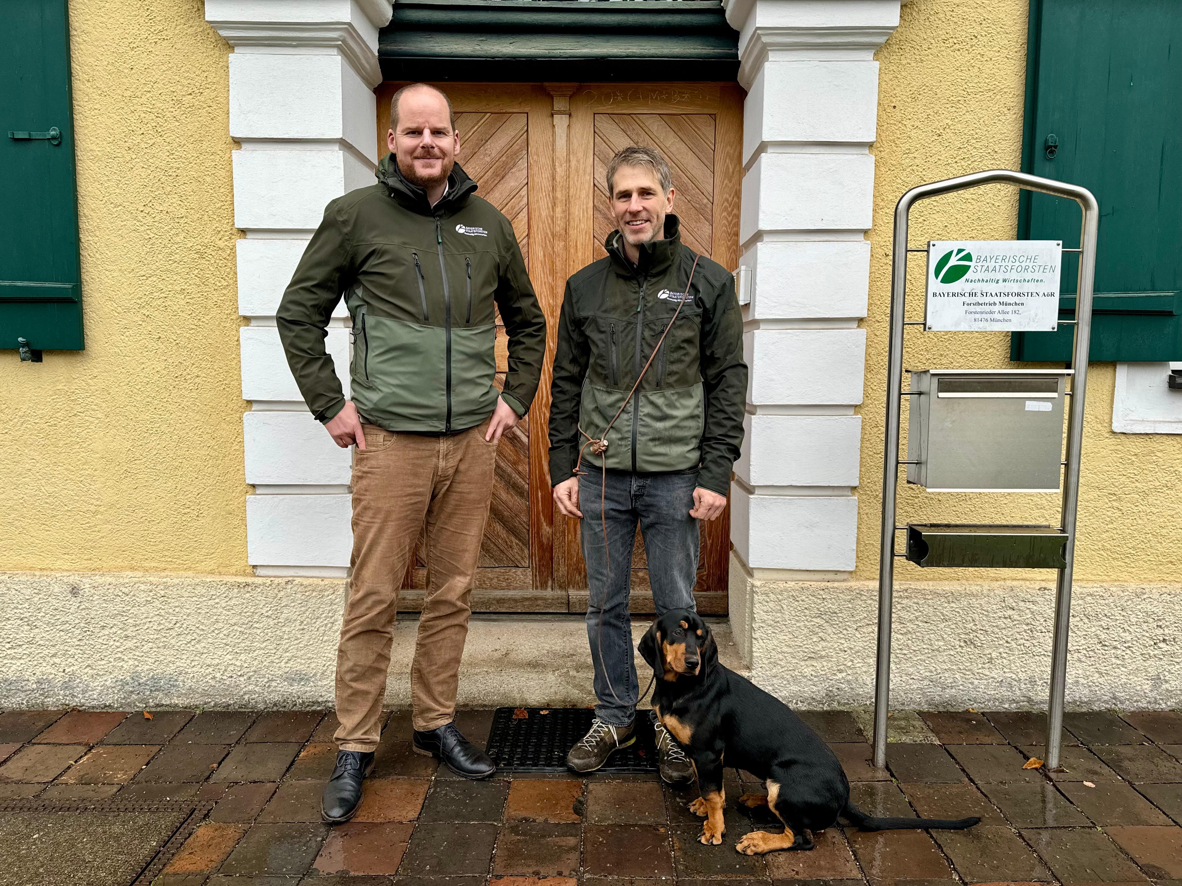 Zwei Menschen vor Haus mit Hund