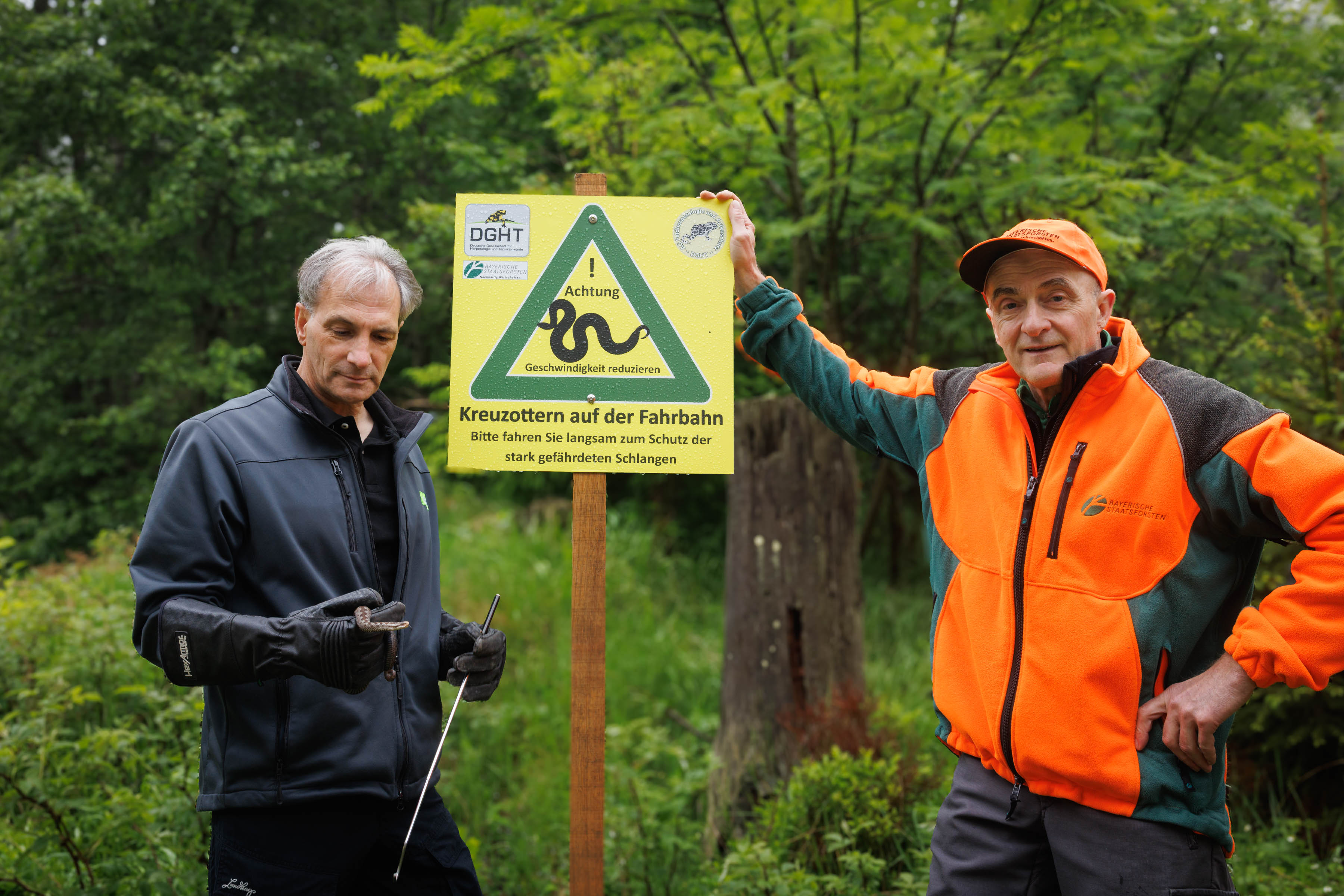 Neue Schilder zeigen Kreuzotter, davor zwei Forstleute aus Fichtelberg
