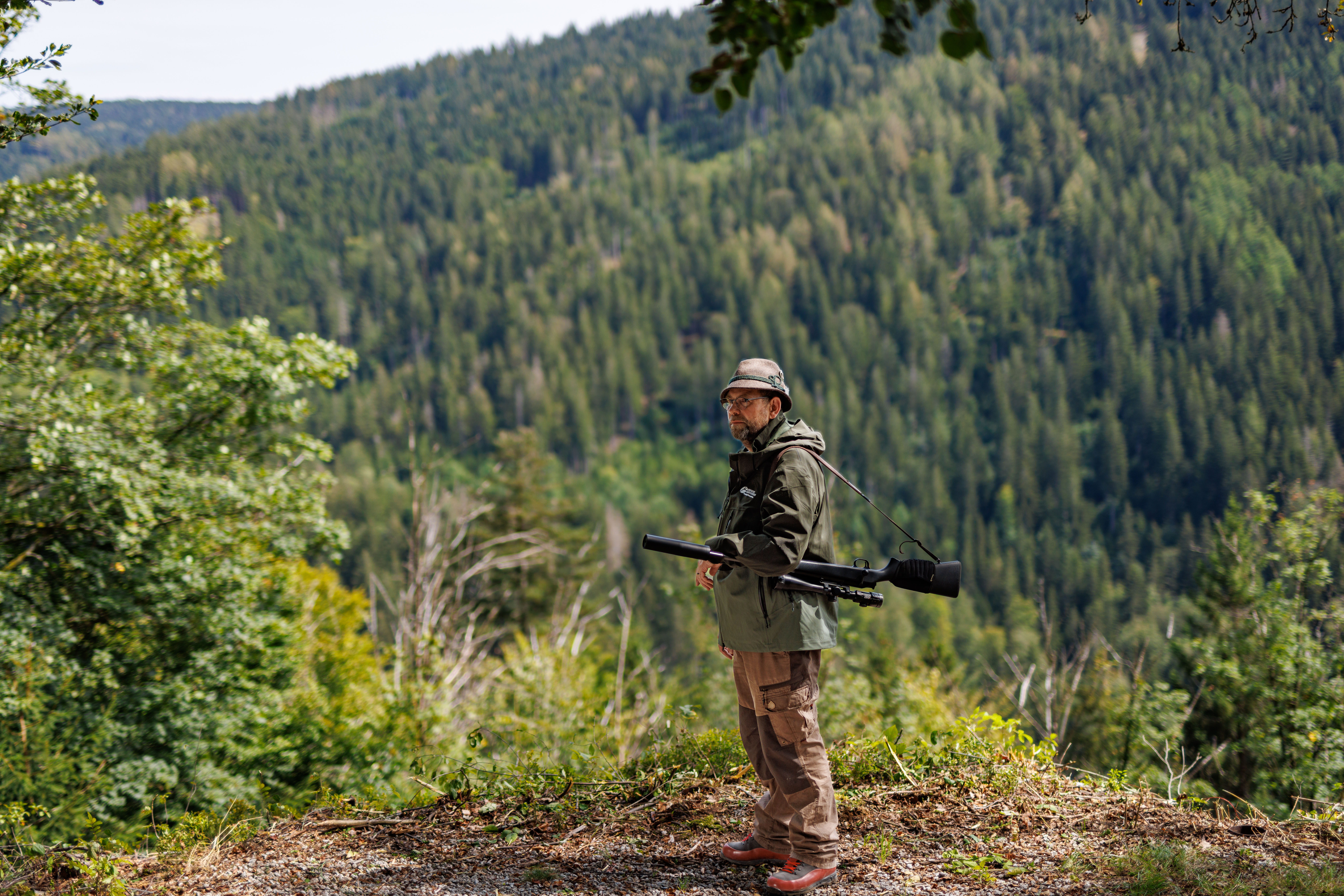 Jäger im Staatswald blickt in die Ferne – mit Gewehr bereit für eine verantwortungsvolle Jagd im Einklang mit der Natur.
