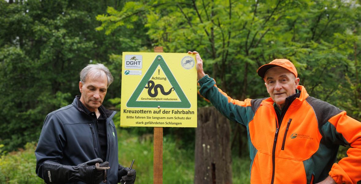 Neue Schilder zeigen Kreuzotter, davor zwei Forstleute aus Fichtelberg