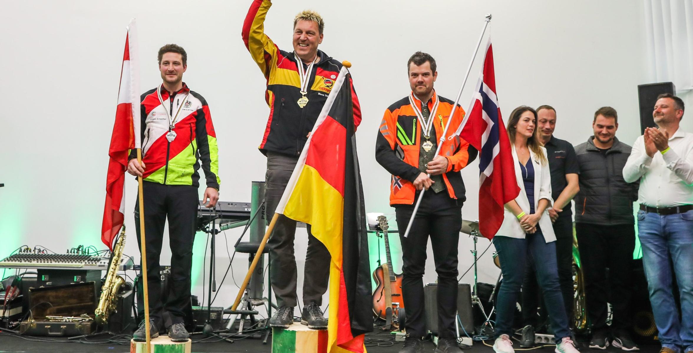Auf dem Siegertreppchen für die Disziplin Entasten. Marco Trabert auf Platz 1, er freut sich sichtlich mit Deutschlandflagge in der Hand.