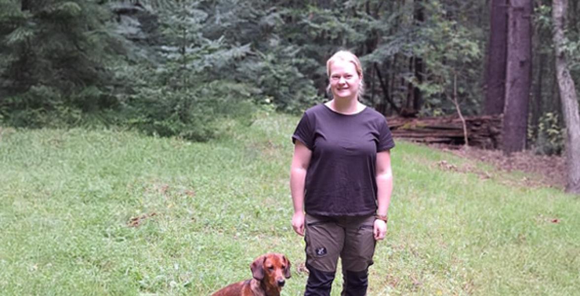 Revierleiterin mit Hund vor einem Wald